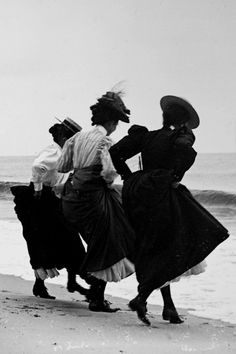 black and white photograph of three women walking on the beach with their backs turned to the camera