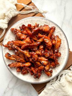 a white plate topped with chicken wings covered in sauce on top of a wooden table