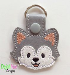 a gray and white cat shaped key fobring with an embellishment on it