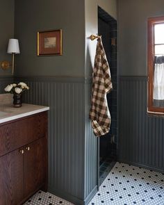 a bathroom with gray walls and black tile flooring, two towels hanging on the wall