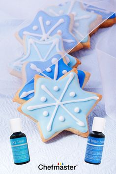 some decorated cookies with blue and white icing next to bottles of deodorant