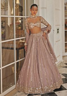 a woman standing in front of a window wearing a pink and gold gown with sequins on it