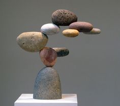 a sculpture made out of rocks sitting on top of a white pedestal