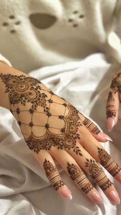 two hands with henna tattoos on them, one is showing off the intricate design