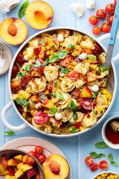 a pan filled with pasta and vegetables on top of a blue table next to other dishes