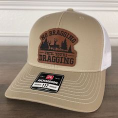 Join the ranks of hunters who understand the art of subtlety. Order your "No Bragging Until You're Dragging" Leather Patch Hat now and wear your love for the hunt! 🦌🧢 Specifications: 🧢 Richardson original 112 trucker; adjustable for the perfect fit 🎩 60/40 cotton/polyester blend for comfort 📏 One size fits most 🏷️ Expertly laser engraved leatherette patch design 📦 Ships in 2 to 3 business days from our Orlando Studio Care Instructions: 🚫 Do not wash; spot clean only Please Note: 🌈 Color Hat Patch Ideas For Men, Leather Patch Ideas, Leather Patch Hat Ideas, Leather Hat Patch, Orlando Studios, Funny Trucker Hat, Hat Bar, Leather Patch Hat, Engraving Ideas