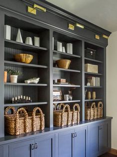 a large bookcase with baskets on top of it and other items in the back