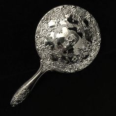 an ornate silver spoon on a black background with the image of a woman's face