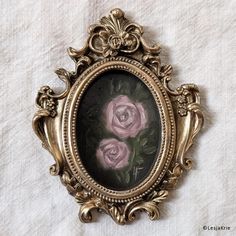 an ornate gold frame with pink roses painted on the inside and in between it's sides