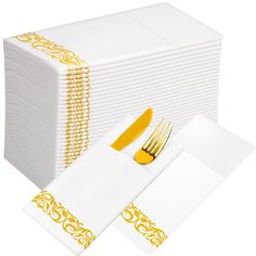 a stack of white napkins with gold trim and a yellow fork on the side