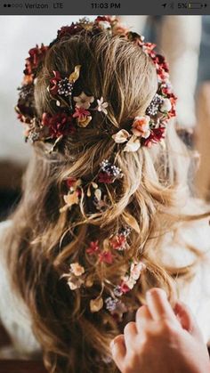 a woman is getting her hair done with flowers in her hair and an orange bottle next to her