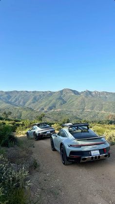 three sports cars parked on the side of a dirt road