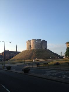 an old castle sitting on top of a hill in the middle of a city street