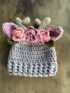 a crocheted hat with flowers on it sitting on top of a wooden table