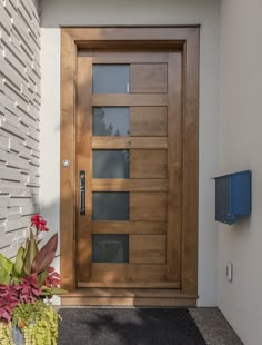 a modern wooden door with glass panels on the side of a house next to a flower pot