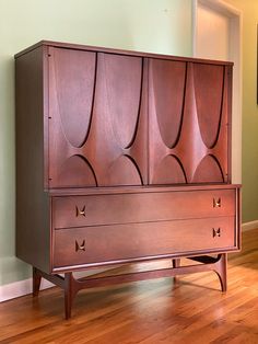 an old wooden cabinet sitting on top of a hard wood floor next to a wall