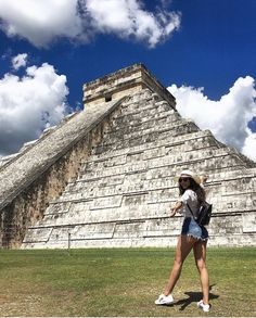 a woman walking in front of an ancient pyramid