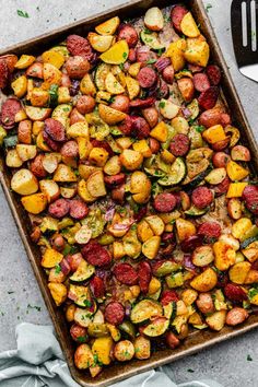 a pan filled with roasted vegetables on top of a table next to a knife and fork