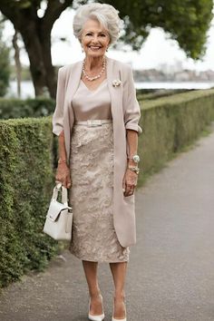 an older woman in a dress and jacket is walking down the street with her purse