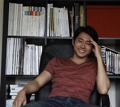 a man sitting in a chair next to a book shelf