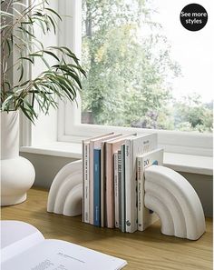 a stack of books sitting on top of a table next to a window