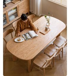 a woman sitting at a wooden table with an open book