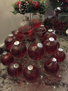 a table topped with lots of glasses filled with red liquid next to pine cones and christmas decorations