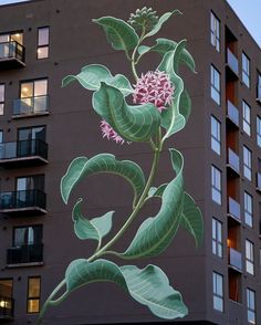 a large mural on the side of a building with leaves and flowers painted on it