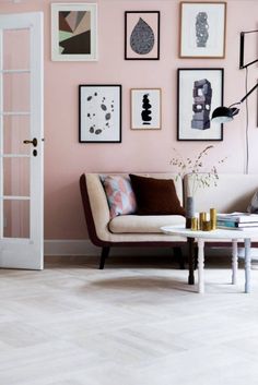 a living room with pink walls and pictures on the wall