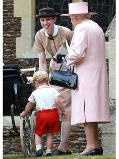 a woman in a pink coat and hat standing next to a little boy with a wheel chair