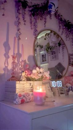 a white dresser topped with a mirror next to a table filled with flowers and candles