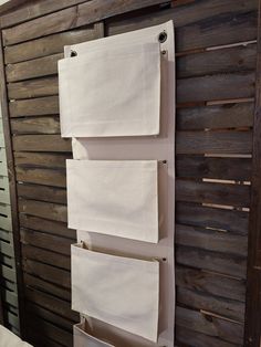 three white towels hanging on a wooden wall