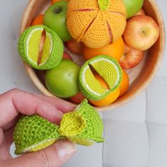 a person is holding an apple and oranges in front of a bowl of fruit