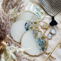 three white and blue plates sitting on top of a table next to other items with gold accents