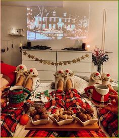 two people are sitting on the bed with food in front of them and watching tv