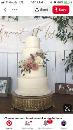 a white wedding cake with pink flowers and greenery sits on a wooden table in front of a sign that says sweet it us