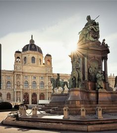 the sun shines brightly behind a statue in front of a building with statues on it