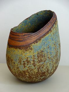 a brown and green vase sitting on top of a table