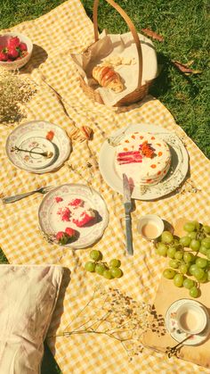 a picnic table set up with plates and bowls of fruit on it, including grapes