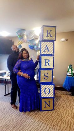 a pregnant woman standing next to a giant wooden block that says karson on it