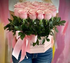 a woman is holding a bunch of pink roses in her pocket with a ribbon around it