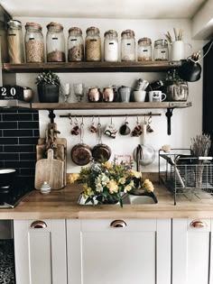 a kitchen with lots of pots and pans on the shelf above the sink,