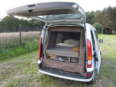 the back end of a white van with an open hatchback and bed in it