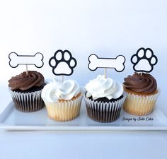 three cupcakes with chocolate frosting and dog bone toppers on a plate