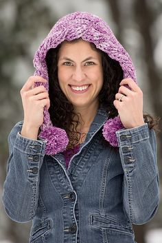 a woman wearing a purple hat and denim jacket with her hands on her hips, smiling at the camera