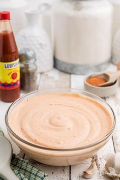 a bowl filled with sauce sitting on top of a table next to garlic and other ingredients