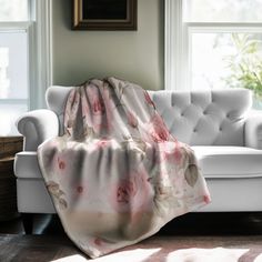 a white couch with a pink flowered blanket draped over it