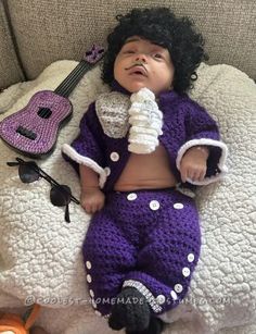 a baby doll laying on top of a bed next to a guitar and other items