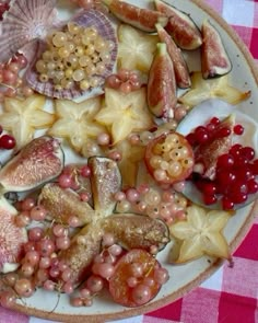 a plate full of fruit and shells on a checkered tablecloth with pink gingham cloth