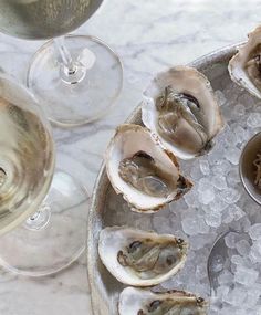 oysters and wine are served on an ice tray